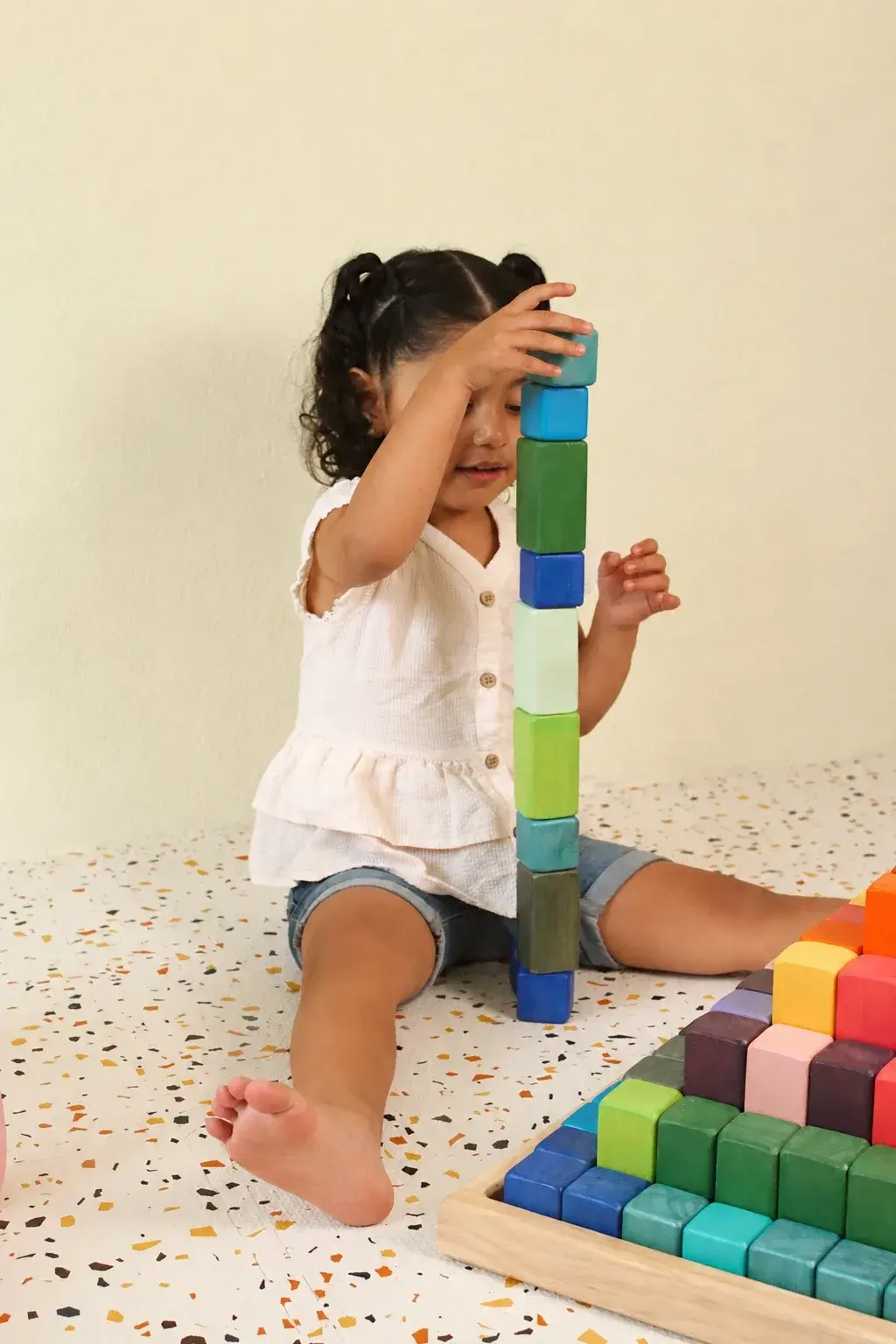 Niña apilando bloques de madera de colores en una torre durante una sesión